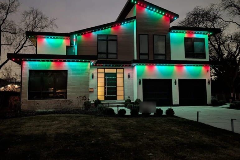 Modern home with permanent roofline lights glowing teal and red